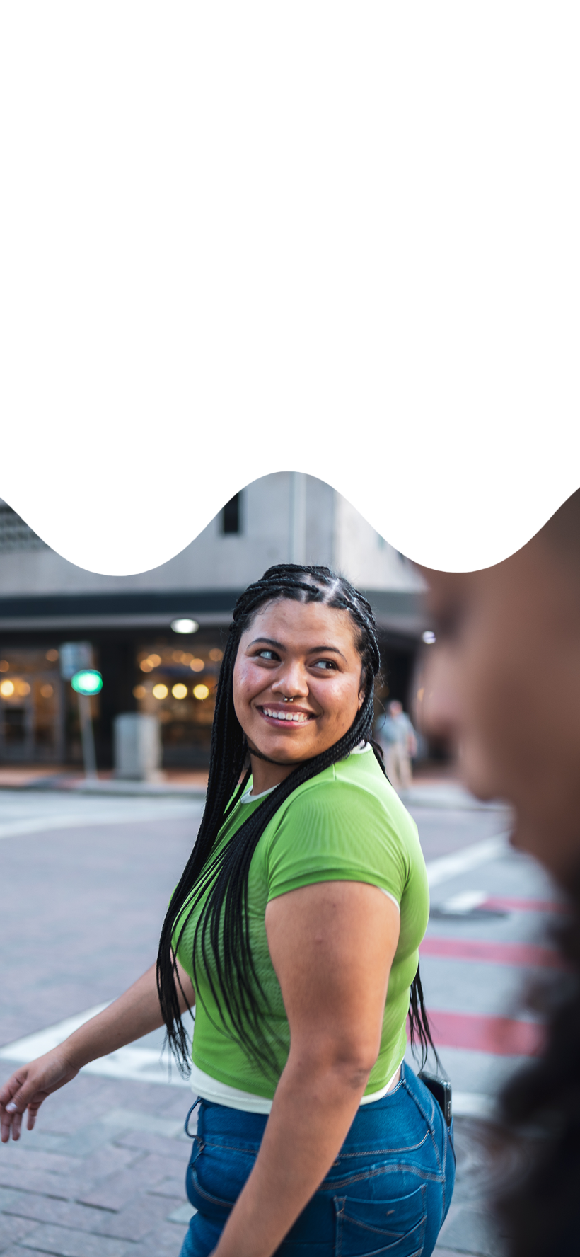 a young woman glancing back with a smile as she crosses a city street